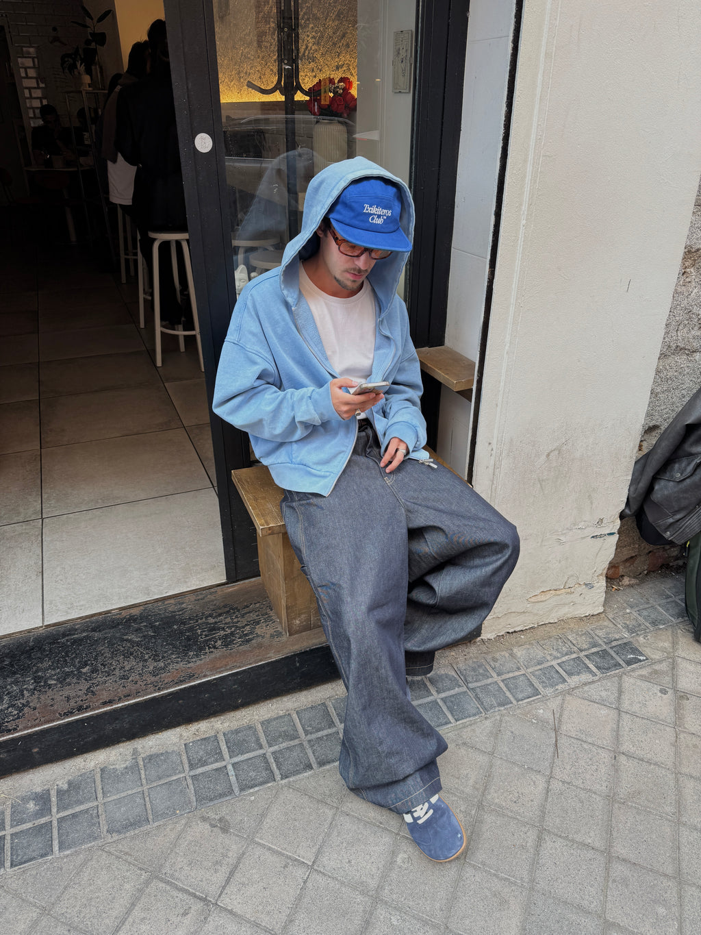 Persona con gorra y sudadera azul llevando zapatillas barefoot Atlantic Ocean azul marino en ciudad — ARNASA