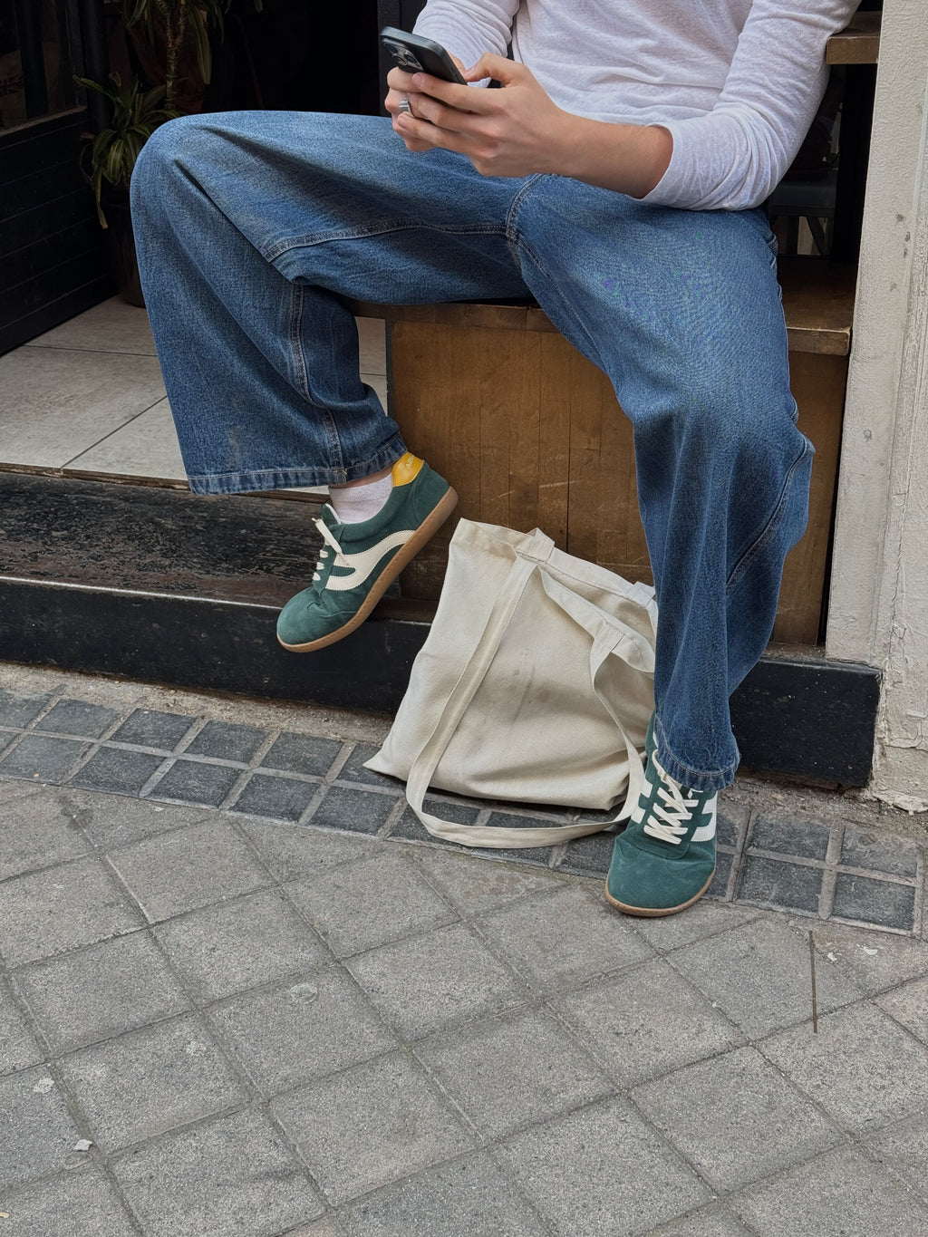 Persona sentada en calle con zapatillas barefoot Atlantic Forest verde bosque en entorno urbano — ARNASA