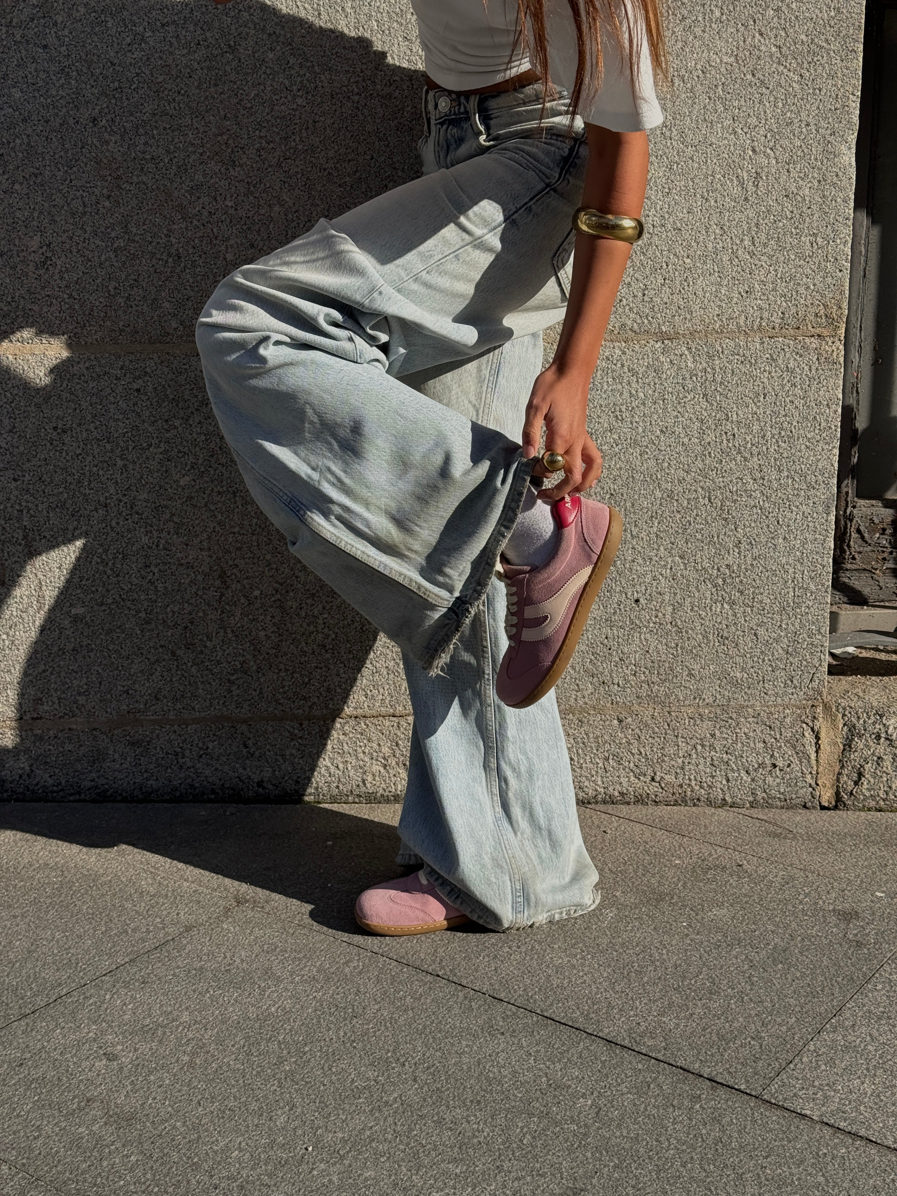 Mujer con vaqueros sujetando zapatilla barefoot Atlantic Bloom rosa empolvado en exterior — ARNASA